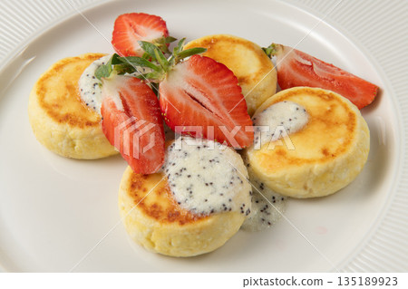 Cheesecakes with poppy seeds and strawberry topping on white plate Cheesecakes with poppy seeds and strawberry topping on white plate 135189923