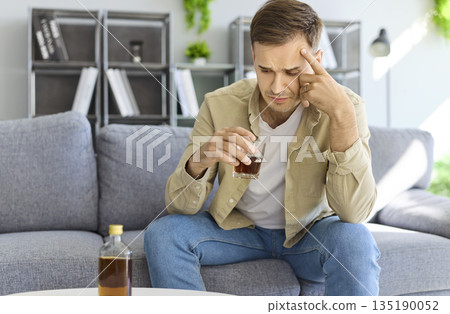 Struggle against alcohol addiction in man with stress and anxiety holding glass 135190052