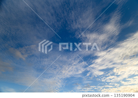 The serene blue sky is dotted with soft, wispy clouds that create a picturesque scene 135190904