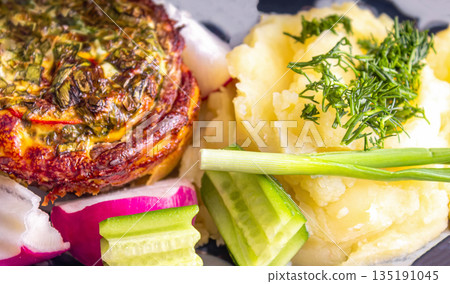 Baked meat with cheese and mashed potatoes with fresh vegetables as a side dish Baked meat with cheese and mashed potatoes with fresh vegetables as a side dish 135191045