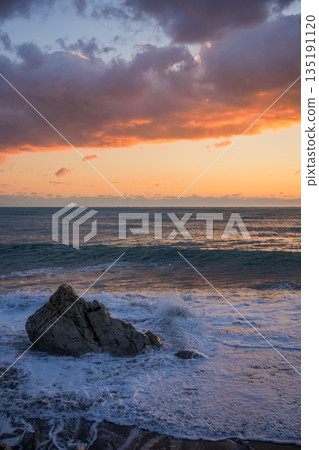 Vertical Sunset Over Sea with Large Coastal Rock Vertical Sunset Over Sea with Large Coastal Rock 135191120