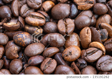 Closeup coffee beans, Dark roasted oily coffee beans, Cracked surface espresso beans with intense aroma, Deep brown black oily coffee beans with smoky aroma and rich flavor Closeup coffee beans, Dark roasted oily coffee beans, Cracked surface espresso beans with intense aroma, Deep brown black oily coffee beans with smoky aroma and rich flavor 135191262