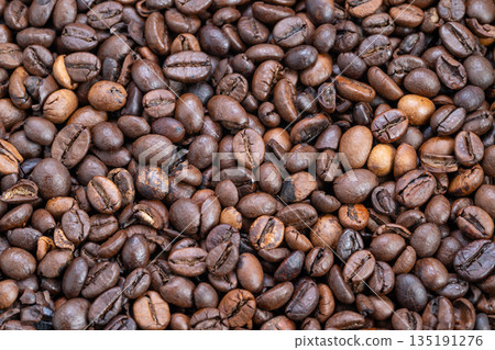 Closeup roasted coffee beans texture showing glossy medium-dark roast, warm brown tones and subtle oil sheen creating cozy breakfast mood for packaging and lifestyle branding 135191276
