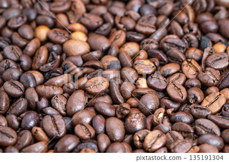 Closeup dark roasted coffee beans piled with glossy oil sheen, deep brown tones, tight macro framing emphasizes texture and rich aroma for specialty roast marketing Closeup dark roasted coffee beans piled with glossy oil sheen, deep brown tones, tight macro framing emphasizes texture and rich aroma for specialty roast marketing 135191304