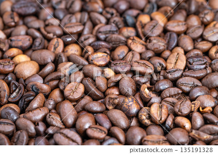 Macro dense roasted coffee beans arranged in uniform pile, deep dark tones and subtle sheen, ideal for wholesale packaging, supply catalogs and background textures 135191328