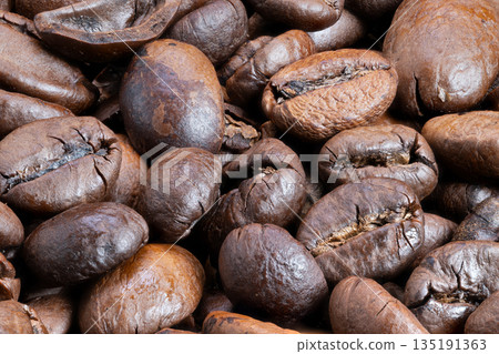 Coffee bean closeup, Intimate shot capturing oily sheen and cracks of freshly roasted beans, Closeup image emphasizing rich textures and warm ambiance of gourmet coffee beans 135191363