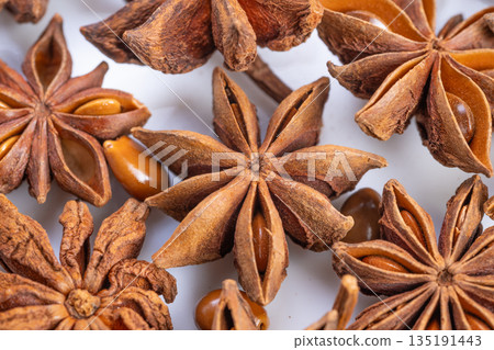 Richly textured star anise pods, Closeup of glossy starshaped spice pods, Detailed image showcasing warm brown star anise with glossy seeds in cozy kitchen setting 135191443