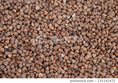 Unprocessed buckwheat seeds showcase rustic texture, Closeup photograph of uncooked buckwheat showcases textured grains ideal for healthy recipes and home cooking 135191472