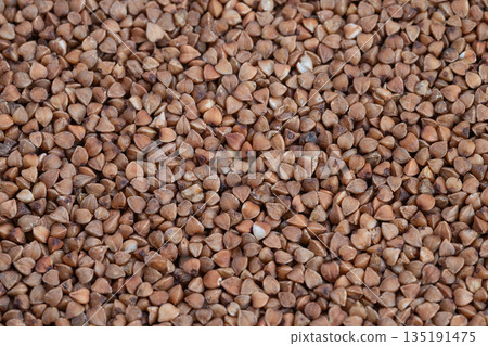Buckwheat kernels display, Closeup of buckwheat grains storage, Detailed image of buckwheat groats in heap, Macro photograph showing bulk buckwheat kernels for packaging visuals 135191475