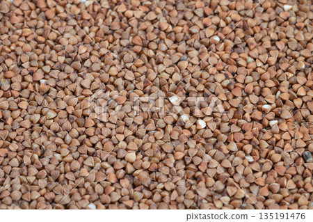 Raw buckwheat grains, Detailed image of buckwheat kernels used in cooking, Macro view of coarse buckwheat groats demonstrating rich texture and nutritional benefits for meals 135191476