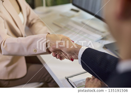 Handshake in modern office sealing hiring agreement between businessman and woman 135191506