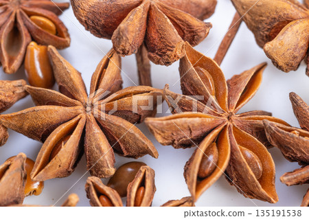 Warm star anise pods evoke holiday baking scene, cozy atmosphere with spice notes, textured pods and glossy seeds suggesting infusion into seasonal recipes and festive desserts 135191538