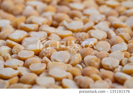 Detailed image of bright yellow legumes, Closeup shot highlighting textured surface of split yellow peas with scattered groats for culinary and nutritional visualization 135191576
