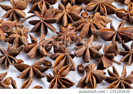 Close up star anise cluster on white surface evokes pantry mood, warm brown pods and tiny seeds arranged in textured pattern for culinary product visuals and recipe content Close up star anise cluster on white surface evokes pantry mood, warm brown pods and tiny seeds arranged in textured pattern for culinary product visuals and recipe content 135191630