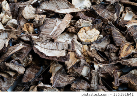 Dehydrated forest fungi textures, Rustic dried mushroom caps and stems display, Artisanally dried forest mushrooms with textured caps and stems in warm kitchen setting 135191641