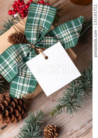 Christmas square gift tag mockup with present box on rustic background Christmas square gift tag mockup with present box on rustic background 135191711