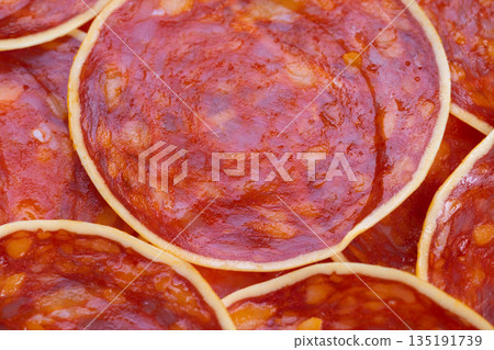 Spicy meat slices, Closeup of seasoned chorizo slices with cheese and paprika shine, Detailed view of overlapping spicy sausage rounds with cheese on textured surface 135191739