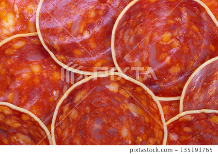 Tapas chorizo slices layered on rustic board, evoking social gathering vibe with savory aroma and glossy spice flecks perfect for party menu and social media food posts 135191765