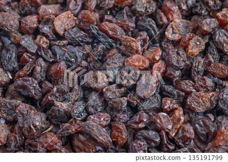 Dried fruit texture, Sundried grapes with shine, Glowing dried grapes offering rich flavor, Brightly shining dried grapes showcasing moistness and diverse brown coloration Dried fruit texture, Sundried grapes with shine, Glowing dried grapes offering rich flavor, Brightly shining dried grapes showcasing moistness and diverse brown coloration 135191799