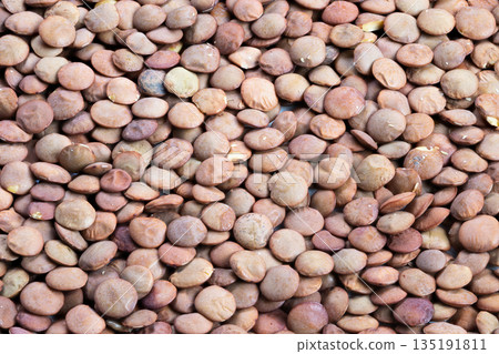 Macro shot showing earthy colored lentils with subtle hues and textures, Intimate view of textured brown lentils illuminated by warm market lighting and rustic ambiance Macro shot showing earthy colored lentils with subtle hues and textures, Intimate view of textured brown lentils illuminated by warm market lighting and rustic ambiance 135191811