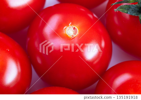 Close up glossy cherry tomato center, intense red sheen and mirrorlike skin, studiolit surface conveying premium culinary garnish, ideal for chef plating and gourmet food styling 135191918