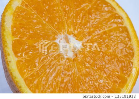 Juicy citrus closeup, Vivid orange slice with juice, Bright citrus segment with glossy pulp and zest, Fresh orange piece with sparkling juice droplets and vibrant peel 135191938
