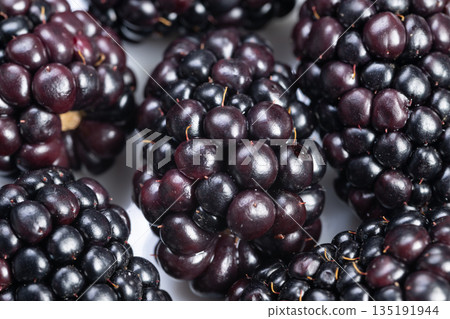Shiny dark berries under studio light, Blackberries with reflective gloss in minimalist setting, Studio shot showcasing glossy blackberries with jewellike appearance Shiny dark berries under studio light, Blackberries with reflective gloss in minimalist setting, Studio shot showcasing glossy blackberries with jewellike appearance 135191944