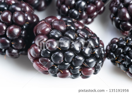 Macro blackberries with glossy highlights and depth, strong reflections and tight focus on drupelet surface, styled for highend food photography, stock libraries and editorial use 135191956