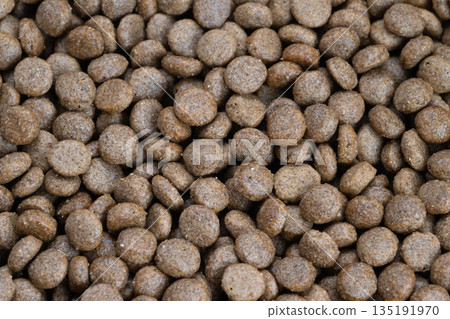 Macro view premium kibble with grain, dense round pellets with fine coating, crisp texture, studiolit closeup ideal for product photography and premium pet nutrition marketing 135191970