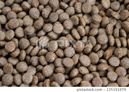 Closeup production batch pet kibble highlighting uniform sizing and textured surfaces, implies industrial quality control, bulk processing, neutral lighting for commercial use Closeup production batch pet kibble highlighting uniform sizing and textured surfaces, implies industrial quality control, bulk processing, neutral lighting for commercial use 135191979