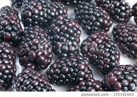 Juicy berries improve sweet dishes, Richly colored ripe blackberries adorn culinary presentations, Deeply hued blackberries used as elegant decoration for desserts 135192003
