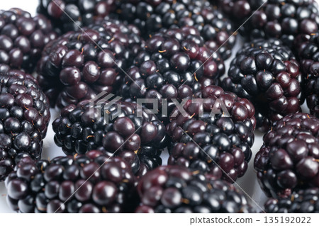 Macro shot of shiny blackberries featuring dew and detailed drupelets, Highresolution macro image showcasing glossy blackberries with dew and intricate drupelet textures 135192022
