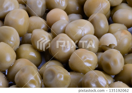 Closeup of glossy preserved peas, Detailed view of peas with smooth surfaces, Detailed closeup highlighting texture and sheen of preserved peas in subdued color scheme Closeup of glossy preserved peas, Detailed view of peas with smooth surfaces, Detailed closeup highlighting texture and sheen of preserved peas in subdued color scheme 135192062