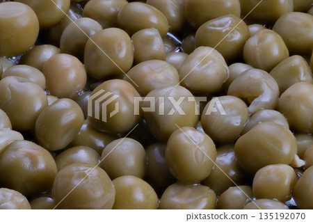 Cluster of canned green peas glistening with brine, neutral kitchen lighting, ideal pantry staple for salads, soups, quick lunches, convenience packing and meal prep visuals 135192070