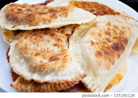 Late night tasty treat, Delicious greasy chebureki served as nighttime comfort food, Indulgent fried chebureki arranged beautifully on plate for midnight snacking pleasure 135192126