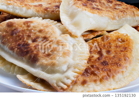 Street food style chebureki delight, Rustic street snack featuring crispy crust and juicy interior, Portable street vendor snack with crunchy edges and savory stuffed filling 135192130