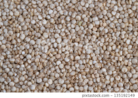 Detailed beige quinoa grains imagery, Closeup of beige quinoa seeds with intricate surface detail, Magnified view highlighting fine texture and round shape of quinoa grains 135192149