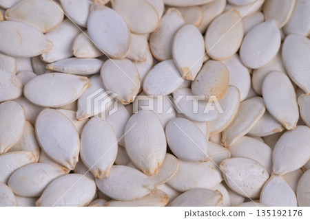 Fine textured pumpkin seeds with soft shadows and neutral backdrop, Detailed closeup of pumpkin seed shells with subtle shadows and neutral tones for design purposes 135192176