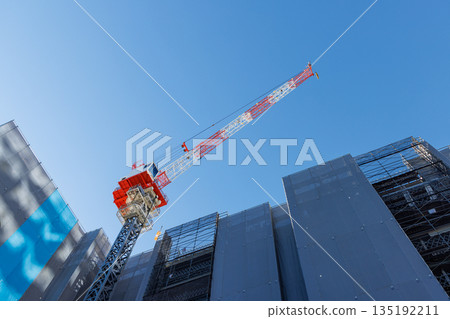 A large construction crane stretching high into the blue sky A large construction crane stretching high into the blue sky 135192211