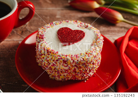 Valentine's Day background. Cake with red heart and cup of coffee on table. Love celebration Valentine's Day background. Cake with red heart and cup of coffee on table. Love celebration 135192243