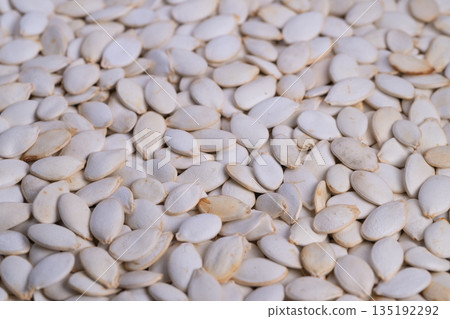 Closeup of salted pumpkin seeds, Detailed view of salted pumpkin seeds on surface, Highdefinition image showcasing pumpkin seeds with fine salt dust on smooth ivory shells Closeup of salted pumpkin seeds, Detailed view of salted pumpkin seeds on surface, Highdefinition image showcasing pumpkin seeds with fine salt dust on smooth ivory shells 135192292
