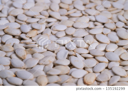 Pumpkin seed closeup, Raw seed layer visualization detailed, Unprocessed pumpkin seeds filling frame, Textured raw pumpkin seeds with soft lighting and neutral background 135192299