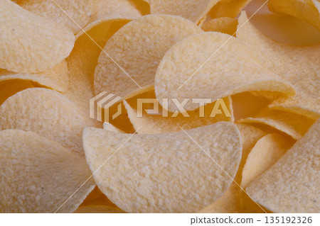 Hero potato chip in sharp focus under spotlight, single crisp edge and visible seasoning, premium snack advertising shot with shallow depth and dramatic contrast Hero potato chip in sharp focus under spotlight, single crisp edge and visible seasoning, premium snack advertising shot with shallow depth and dramatic contrast 135192326