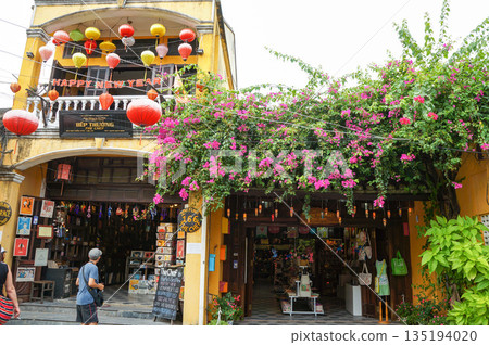 人們經過一棟建築，二樓裝飾著五彩繽紛的燈籠。 135194020