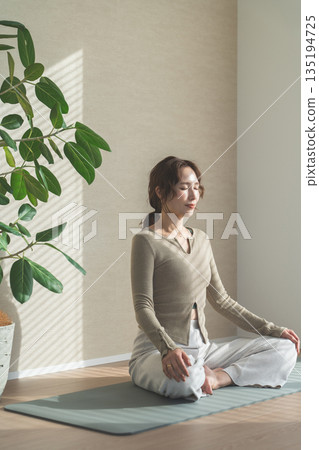 一位女士在自家客廳做瑜珈（放鬆、保健、冥想） 135194725