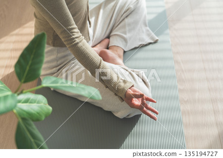 A woman doing yoga in the living room of her home (relaxation, health care, meditation) 135194727