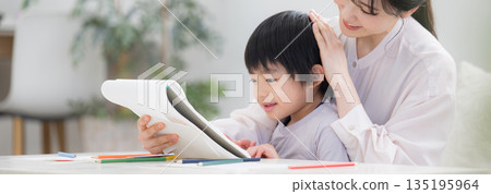 幼兒在媽媽的注視下興致勃勃地學習，並打開筆記本。表揚這個孩子。 135195964
