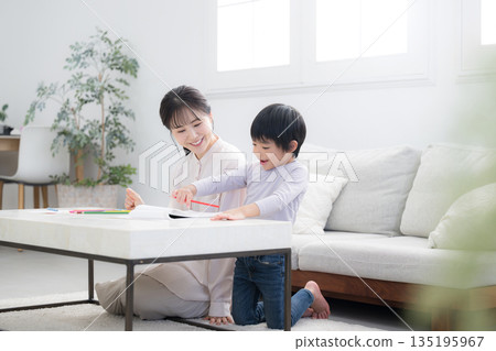 A toddler enjoying learning while being watched over by his mother (mother) 135195967
