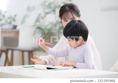 A toddler enjoying learning while being watched over by his mother (mother) 135195968