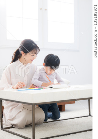 A toddler enjoying learning while being watched over by his mother (mother) 135195971